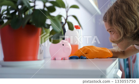 Teen girl in a cozy room cleans drawer with blue rag and wears orange gloves Teen girl in a cozy room cleans drawer with blue rag and wears orange gloves 133055750