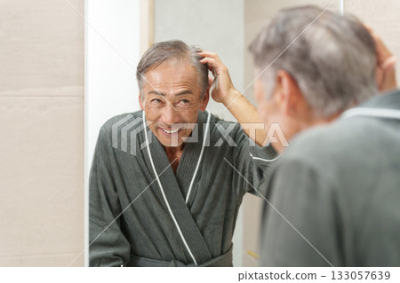 一位頭髮稀疏/禿頭的老年男子在浴室裡檢查自己的頭髮 133057639