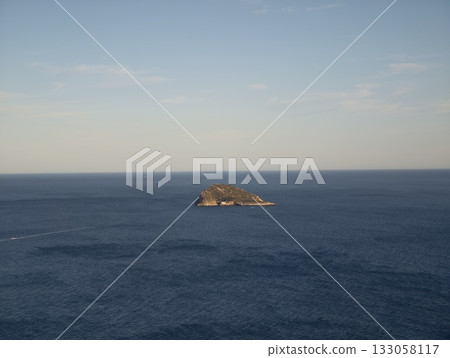 isolated coastal monument, remote solitary island surrounded by peaceful blue waters and clear skies 133058117