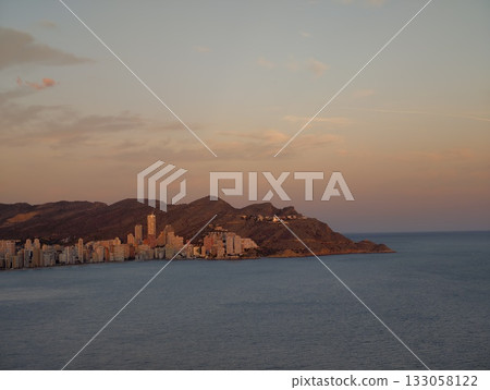 gentle twilight over tranquil seaside cityscape, calm dusk glow illuminating distant city 133058122