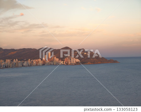 bright seaside panorama, calm ocean with horizon view, gentle sea reflecting colorful sunset hues 133058123