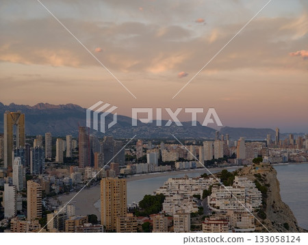 elegant seaside city during sunset hour, vibrant coastal metropolis illuminated by evening golden 133058124