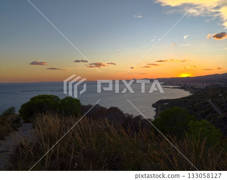 serene sunset landscape, peaceful coastal scene with swaying grasses and silhouetted mountains serene sunset landscape, peaceful coastal scene with swaying grasses and silhouetted mountains 133058127