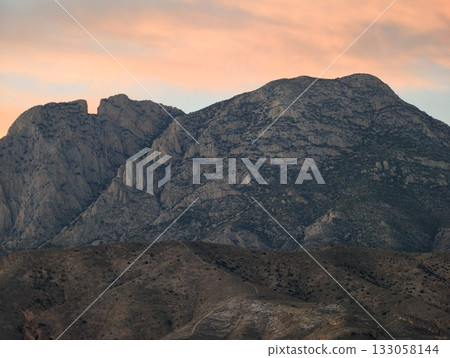 dusk granite landscape, warm sky over rugged terrain, sunset illuminates rocky ridges with peaceful 133058144