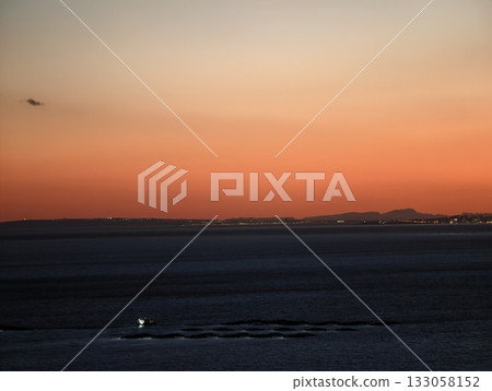 sunset sky over bustling fishing harbor, colorful horizon with boats and shimmering water below 133058152