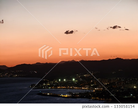 nighttime harbor scene, peaceful night scene of harbor with shimmering reflections and distant city 133058154