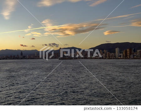 serene coastal cityscape glow, sunset illuminates highrise buildings along tranquil ocean shores serene coastal cityscape glow, sunset illuminates highrise buildings along tranquil ocean shores 133058174
