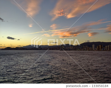evening horizon with mountain scenery, twilight city silhouette against peaceful sea and rugged evening horizon with mountain scenery, twilight city silhouette against peaceful sea and rugged 133058184