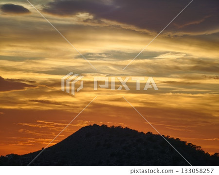 crimson horizon with swirling cloud formations, dramatic evening sky illuminated by fiery hues 133058257