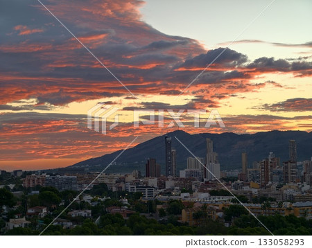 vibrant sunset over metropolitan area with towering glass buildings and scenic mountain backdrop vibrant sunset over metropolitan area with towering glass buildings and scenic mountain backdrop 133058293
