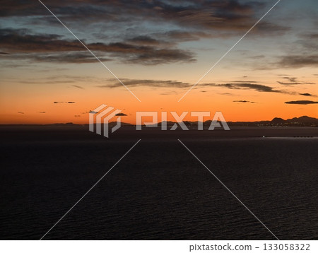 vivid sunset scene, vibrant sunset casting warm tones across ocean with prominent cloud formations vivid sunset scene, vibrant sunset casting warm tones across ocean with prominent cloud formations 133058322
