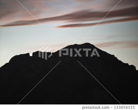 calm ridge silhouette with pastel clouds, serene mountain profile against gentle pastel sky calm ridge silhouette with pastel clouds, serene mountain profile against gentle pastel sky 133058333