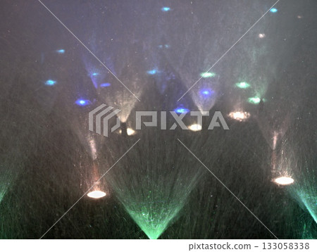 colorful fountain spectacle, crimson and azure sprays with shimmering lights and fog atmosphere 133058338