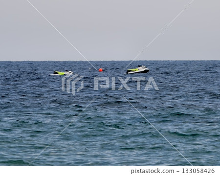 an energetic summer outing featuring riders skimming across blue waves with wakes trailing behind an energetic summer outing featuring riders skimming across blue waves with wakes trailing behind 133058426