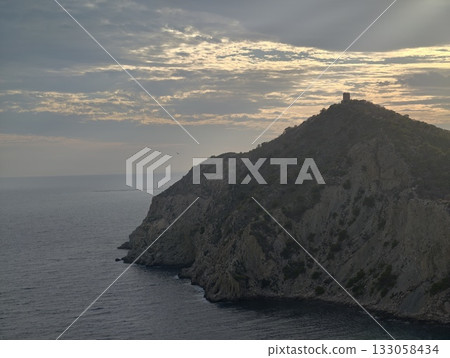 warm hues and striking cloud patterns enhance tranquil seafront cliff scenery during evening 133058434