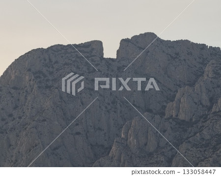 jagged cliffs under dusky sky, dusk reveals sharp rocky faces and ancient geological formations jagged cliffs under dusky sky, dusk reveals sharp rocky faces and ancient geological formations 133058447