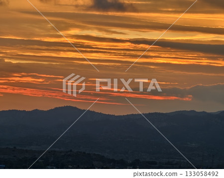colorful evening scenery, vibrant sunset illuminates hills with dramatic cloud formations and hues 133058492