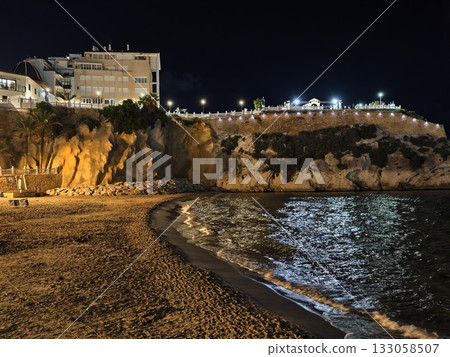 beach night allure, nighttime seaside landscape featuring luminous hotels and reflective sands 133058507