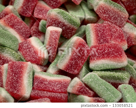 vivid marketstyle gummy sweet display, brightly illuminated watermelon shaped chewy confections 133058521