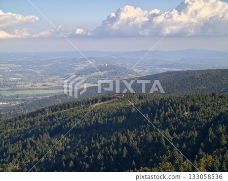 scenic views with peaceful atmosphere, tranquil ridge capped by vibrant clouds over forested expanse 133058536