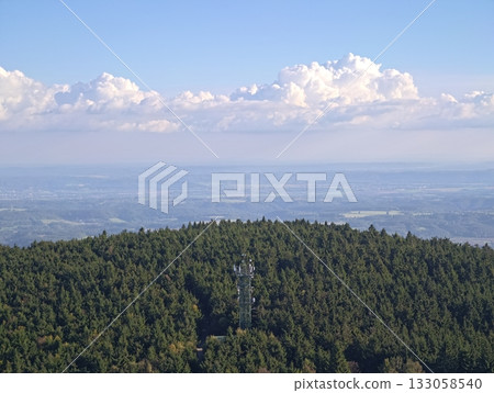 vast vista with lush evergreen cover nestled on undulating hills and distant cloud formations 133058540