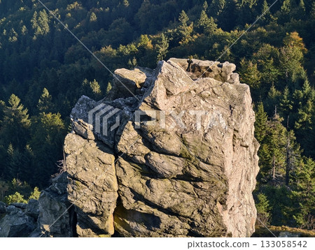 cliff overlooking valley, sunlit granite with pine slopes, rugged terrain with moss and shadows 133058542