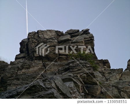 challenging geological structure, tall stratified cliff with cracks and rugged textures under blue 133058551