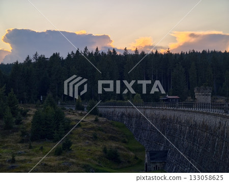 beautiful horizon captured during golden hour, scenic dam with forest and rocky shoreline at sunset 133058625