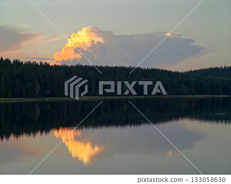 serene evening scene with shining cloud, calm waters mirror bright cloud against dark pine horizon serene evening scene with shining cloud, calm waters mirror bright cloud against dark pine horizon 133058630
