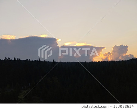 silent twilight sky casting gentle glow on forested ridge with silhouettes and flowing clouds silent twilight sky casting gentle glow on forested ridge with silhouettes and flowing clouds 133058634