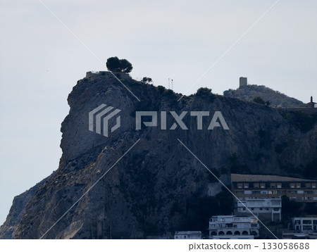 chain of layered buildings on steep cliffs featuring solitary tree and historic ramparts 133058688