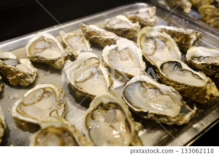 Freshly shucked oysters served on a silver platter during a seafood event in a coastal city in the evening Freshly shucked oysters served on a silver platter during a seafood event in a coastal city in the evening 133062118