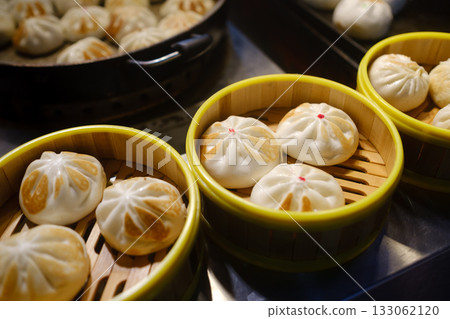 Steamed buns arranged in bamboo baskets at a market stand in the evening, showcasing delicious Asian cuisine and street food culture Steamed buns arranged in bamboo baskets at a market stand in the evening, showcasing delicious Asian cuisine and street food culture 133062120