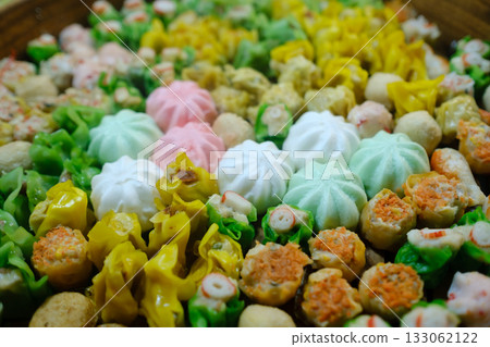 Vibrant assortment of colorful dumplings and snacks displayed beautifully on a platter with green, pink, yellow, and white varieties Vibrant assortment of colorful dumplings and snacks displayed beautifully on a platter with green, pink, yellow, and white varieties 133062122