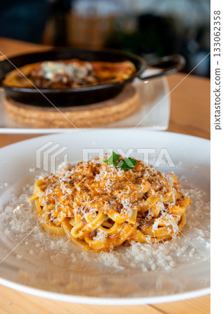 Tagliatelle Bolognese topped with grated cheese is lined up on the tables inside the restaurant. 133062358