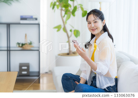 A woman who operates a smartphone in the room 133063076