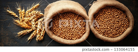 Rustic bounty: Golden wheat ears and burlap sacks filled with grains. 133064155