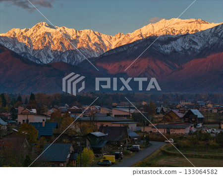 Autumn leaves in the countryside and snow-capped Mt. Goryu and Mt. Karamatsu in Hakuba Village, Nagano Prefecture (aerial shot by drone) 133064582