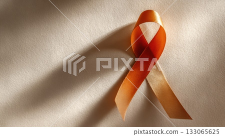 Orange awareness ribbon symbol on beige textured background 133065625