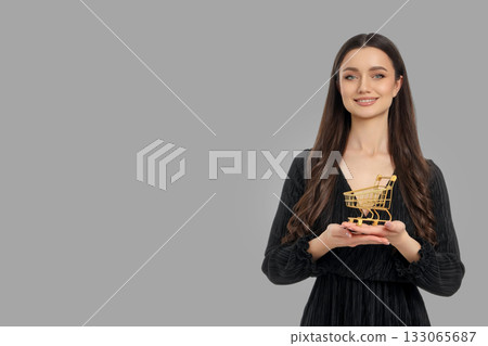 Woman smiles while holding a small shopping cart in a studio 133065687