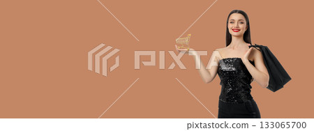 Woman in black sequin dress holding shopping cart and bag 133065700