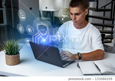 Young man using laptop with digital security icons in modern workspace Young man using laptop with digital security icons in modern workspace 133066209