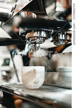 Barista prepares espresso in a cafe with a vibrant atmosphere during morning hours 133066254