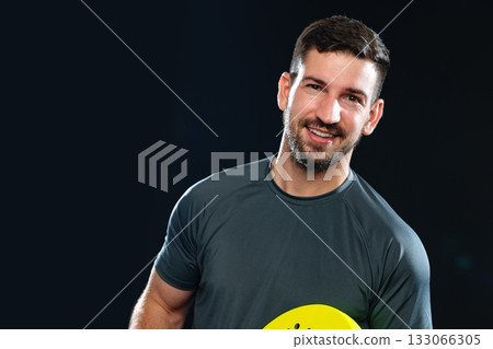 Smiling man in athletic wear holding a bright yellow disc in a studio setting Smiling man in athletic wear holding a bright yellow disc in a studio setting 133066305
