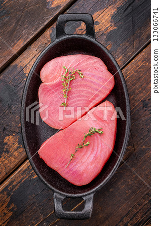 Vibrant raw tuna steak, showcasing its deep red hue, an essential ingredient for sushi enthusiasts and seafood connoisseurs. wooden background. top view 133066741