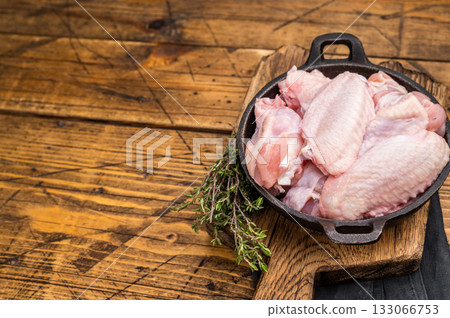 Juicy uncooked chicken wings, a versatile ingredient perfect for frying, baking, or grilling to perfection. wooden background. top view Juicy uncooked chicken wings, a versatile ingredient perfect for frying, baking, or grilling to perfection. wooden background. top view 133066753