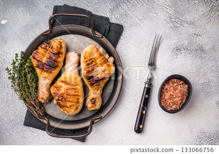 Juicy grilled chicken drumsticks, perfectly charred and bursting with flavor, ideal for a summer barbecue. grey background. top view Juicy grilled chicken drumsticks, perfectly charred and bursting with flavor, ideal for a summer barbecue. grey background. top view 133066756