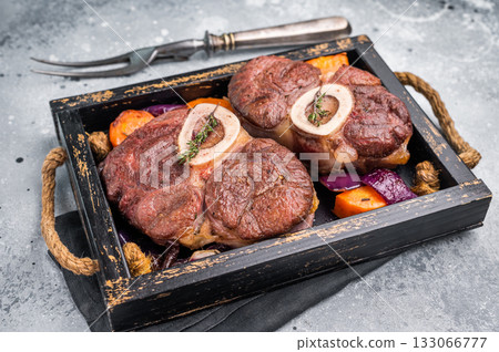 Flavorful ossobuco garnished with fresh herbs, osso buco shank ideal for impressing guests at your next dinner party. grey background. top view Flavorful ossobuco garnished with fresh herbs, osso buco shank ideal for impressing guests at your next dinner party. grey background. top view 133066777