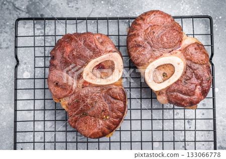 Tender veal osso buco, cross cut shank simmered in rich sauce, a timeless recipe that delights the senses and warms the heart. grey background. top view 133066778