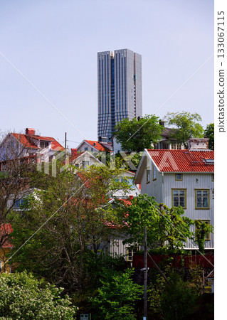 Colony of small wooden historic houses on the Slottsberget mountain with the tallest Scandinavian building Karlatornet skycraper in Lindholmen in background, Gothenburg, Sweden 133067115